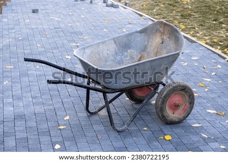 Empty old garden wheelbarrow on a new stone-paved path. Laying of paving slabs.