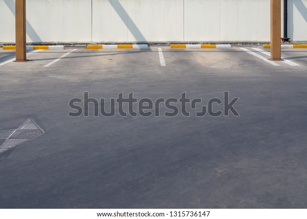 Empty old outdoor parking lot near the wall on\
sunny day with copy\
space.