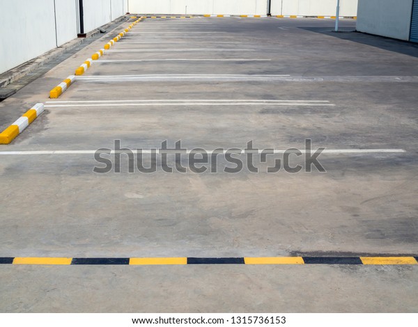 Empty old\
outdoor parking lot with yellow and white line near building and\
white wall on sunny day with copy\
space.
