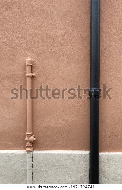 Empty old pink home concrete wall with metal pipe\
of two colors, brown and pink, with white basement that creates two\
sides.