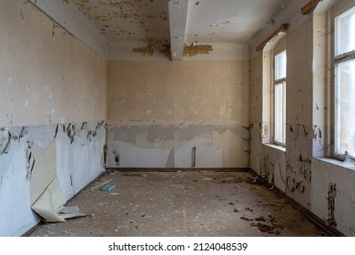Empty old room in an abandoned building. Window light is shining in. Paint is peeling off the walls before renovation. Construction site of an ancient house can be used as abstract background picture.