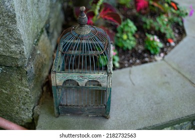 Empty Old Wooden And Metal Bird Cage On Flower Bed Edge