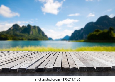 Empty old wooden table in front of blurred background of the lake, mountain, blue sky among bright sunlight on a clear day. Can be used for display or montage for show your products.