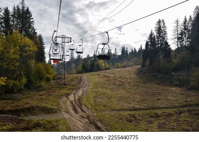 Empty сhairlift on a fall mountain slope with colorful trees. Elevator in the autumn season. Carpathian Mountains, Ukraine