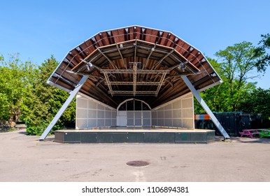 Empty open air stage in a park, with a sound projecting roof and no people on a sunny day