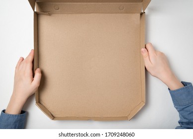 Empty Open Box Of Pizza In Children's Hands On White Background. Top View. Copy Space