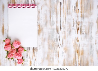 Empty open notebook and pink roses on white wooden rustic background. copy space for design, text. Valentine's day, love, romantic symbol concept. mock up, flat lay