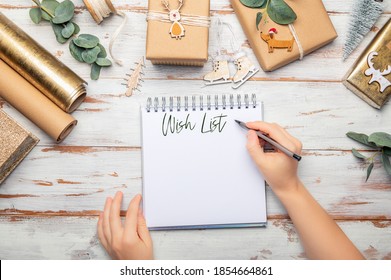 Empty open notebook for writing xmas wish list. Gifts wrapped in recycled brown paper with handmade toppers , christmas background with minimalist style wrapping