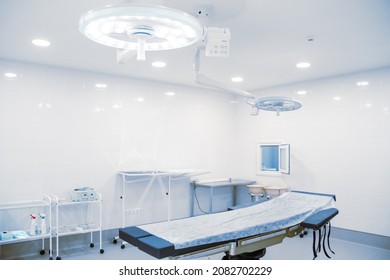 Empty Operating Room In A Hospital. Surgical Equipment With Operating Table. Medical Device For Emergency Patient In Blue Tone Style. Blank Emergency Surgery Room. Clinic Interior For Background.