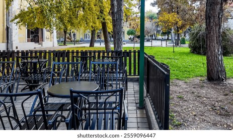 Empty outdoor cafe chairs and tables under autumn trees suggest a serene atmosphere ideal for Thanksgiving outdoor dining - Powered by Shutterstock