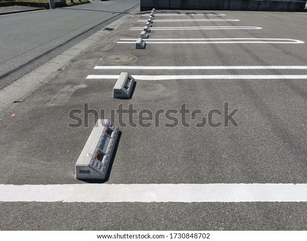 Empty outdoor concrete car parking lot is\
divided for making a slot for the park each car by a white line,\
with cement wheel car\
stopper.