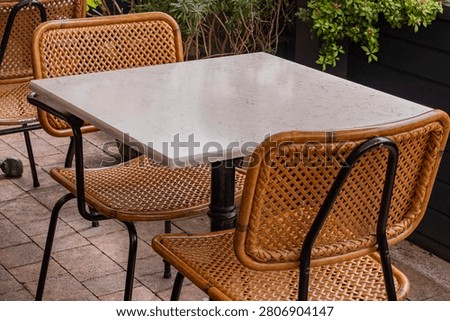Empty Outdoor Restaurant Table with Wicker Chairs and Copy Space