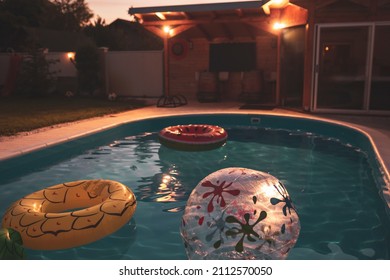 Empty Outdoor Swimming Pool In Holiday Villa Garden With Inflatable Toys And Night Lights. Focus On The Pineapple