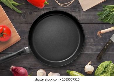 Empty pan on a kitchen table surrounded by vegetarian cuisine ingredients. - Powered by Shutterstock