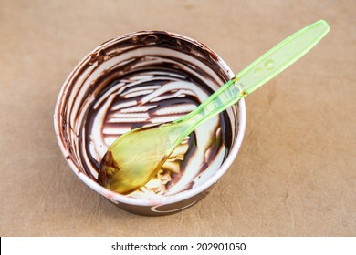 Empty Paper Cup With Remains Of Ice Cream And Plastic Green Spoon