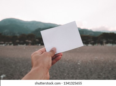 Empty paper note in hand amazing landscape background  Travel   Vacation concept  White piece paper and no text