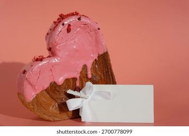 Empty paper note template sample mock up blank for wishes greeting holiday card Heartshaped pastry croissant treat topped with colorful frosting galore. Food experimentation viral dessert baking trend