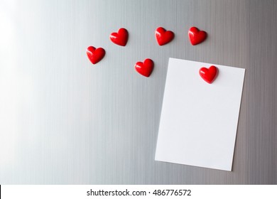 Empty paper sheet on refrigerator door. Note paper with magnetic heart. Valentine send text love message.