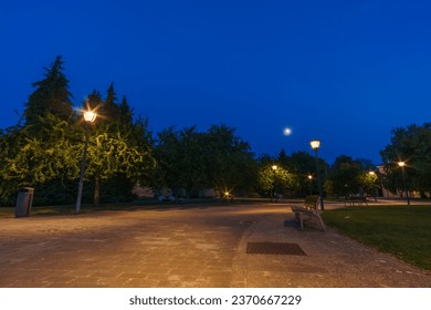 Empty park bench in citadel at night during blue hour with moon on the sky in Pamplona, Navarra, Spain - Powered by Shutterstock