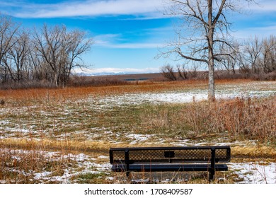 An empty park bench next to Cherry Creek Reservoir
