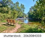 Empty Park bench overlooking a lake,pond called Neshaminy Creek in Tyler State Park in Bucks County,Pennsylvania USA.