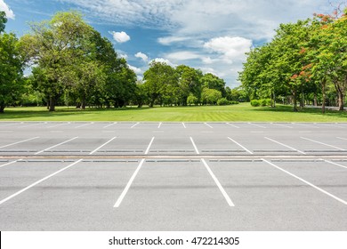 Empty Parking Lot Against Green Lawn In City Park 