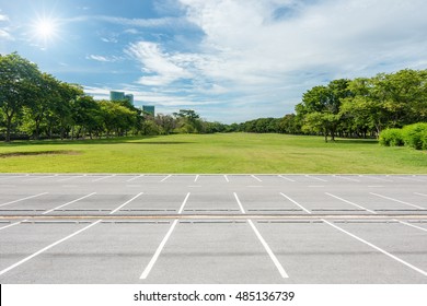 Empty Parking Lot Against Green Lawn In City Park 