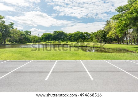 Empty parking lot against green lawn in city park 