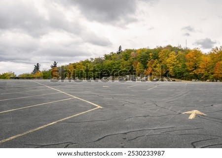 Empty parking lot bordered with autumnal trees on the top of a mountain on a cloudy day