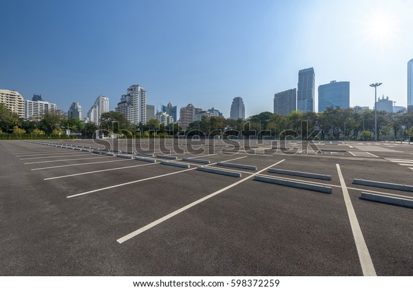 Empty parking lot at city center with blue sky\
and sun reflection
