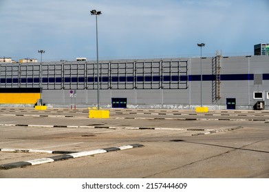 Empty Parking Lot In Front Of Large Gray Industrial Building. Large Industrial Warehouse. Parking Large Warehouse. New Modern And Large Warehouse Building