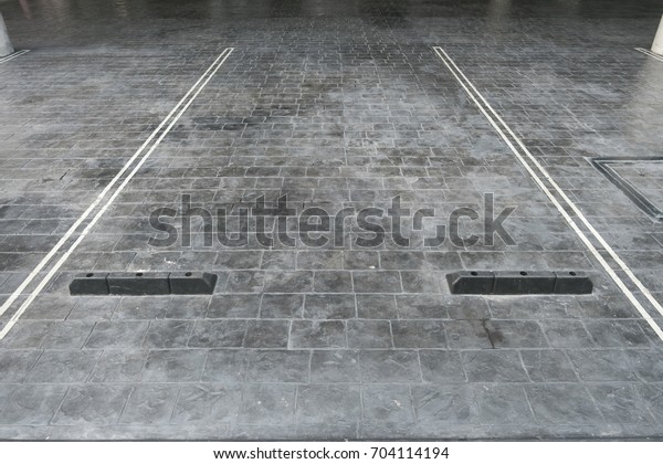 Empty parking lot space for car park, with\
lot line and stopper, in grey concrete\
tile
