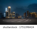 empty parking space in downtown with illuminated modern cityscape and buildings at night.