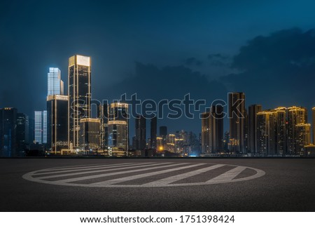empty parking space in downtown with illuminated modern cityscape and buildings at night.