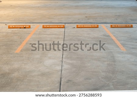 Empty parking space with orange lines on a concrete surface showing a clean layout and organized structure for vehicle positioning.