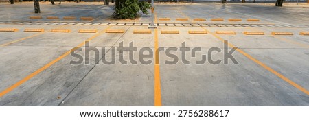 Empty parking space with orange lines on a concrete surface showing a clean layout and organized structure for vehicle positioning.