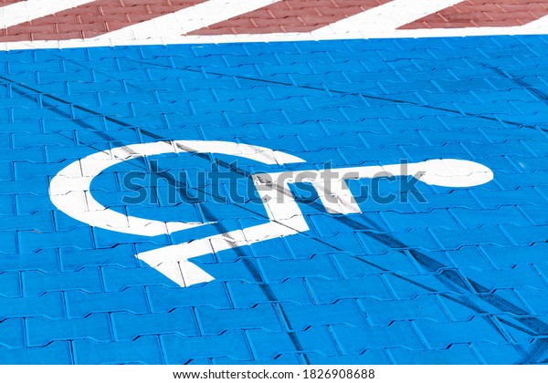 Empty parking spot for the handicapped, blue\
wheelchair symbol on the ground. Parking place for the disabled\
indicator on the pavement in the parking lot area outdoors,\
closeup. Accessibility\
concept