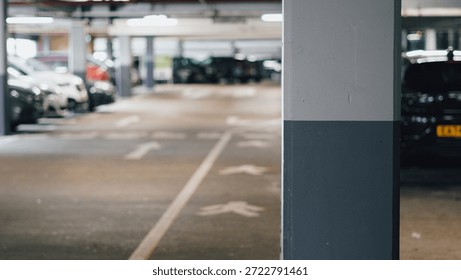 Empty parking structure features vehicles and a concrete pillar in the foreground