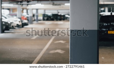 Empty parking structure features vehicles and a concrete pillar in the foreground