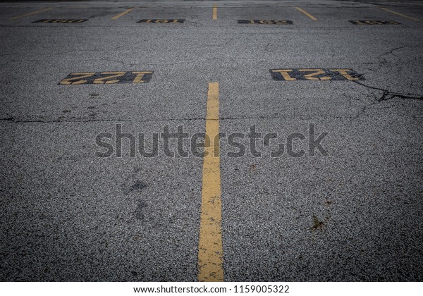 Empty parking\
lot with yellow stripes and\
numbers