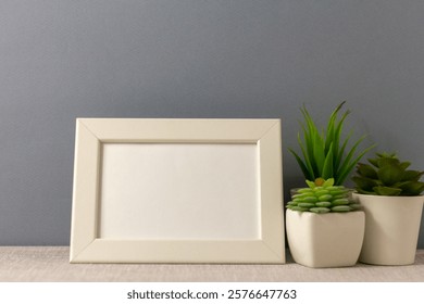 An empty photo frame on the table. Mini pots with succulents. A minimalist-style workspace. A place to copy.