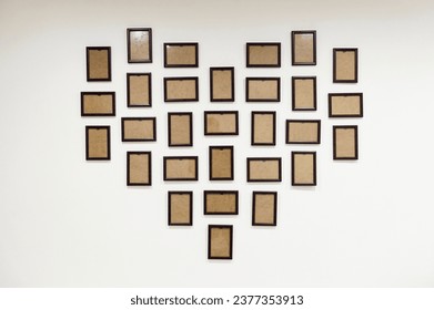 empty photo frames hang on the wall in the shape of a heart. place for photos. dark brown wooden photo frame