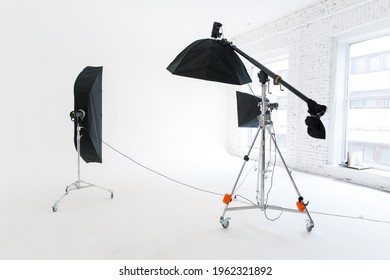 Empty photo studio with lighting equipment. Photographer workplace interior with professional tool set gear. Flash light, white background scenes ready for studio shooting. Modern photographer studio - Shutterstock ID 1962321892