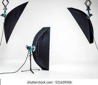 Empty photo studio with lighting equipment on white