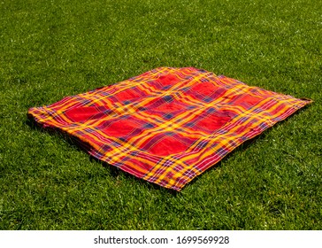 Empty picnic tablecloth on green grass.  Space for text