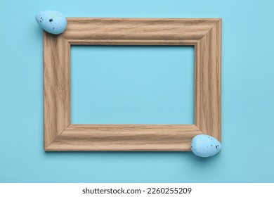Empty picture frame and Easter eggs on color background