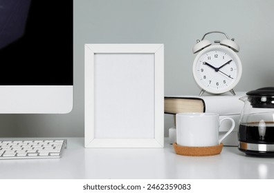 Empty picture frame on table in workspace with computer and coffee cup
