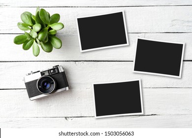 Empty Picture Frames With Photo Camera On White Wooden Table. Top View