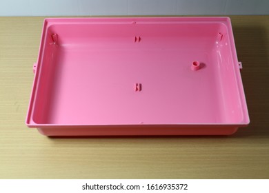 Empty Pink Base Of  Hamster Cage On Wood Desk