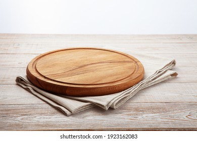 Empty pizza board and canvas tablecloth on white wooden deck. Selective focus.
